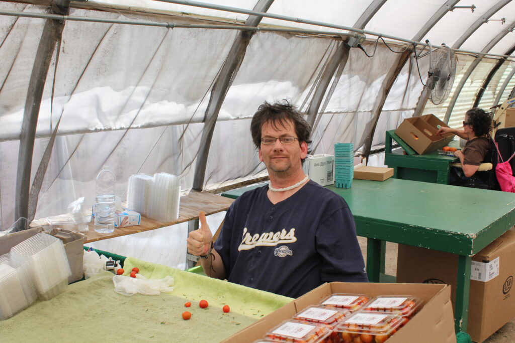 Man sitting at a table in a greenhouse.