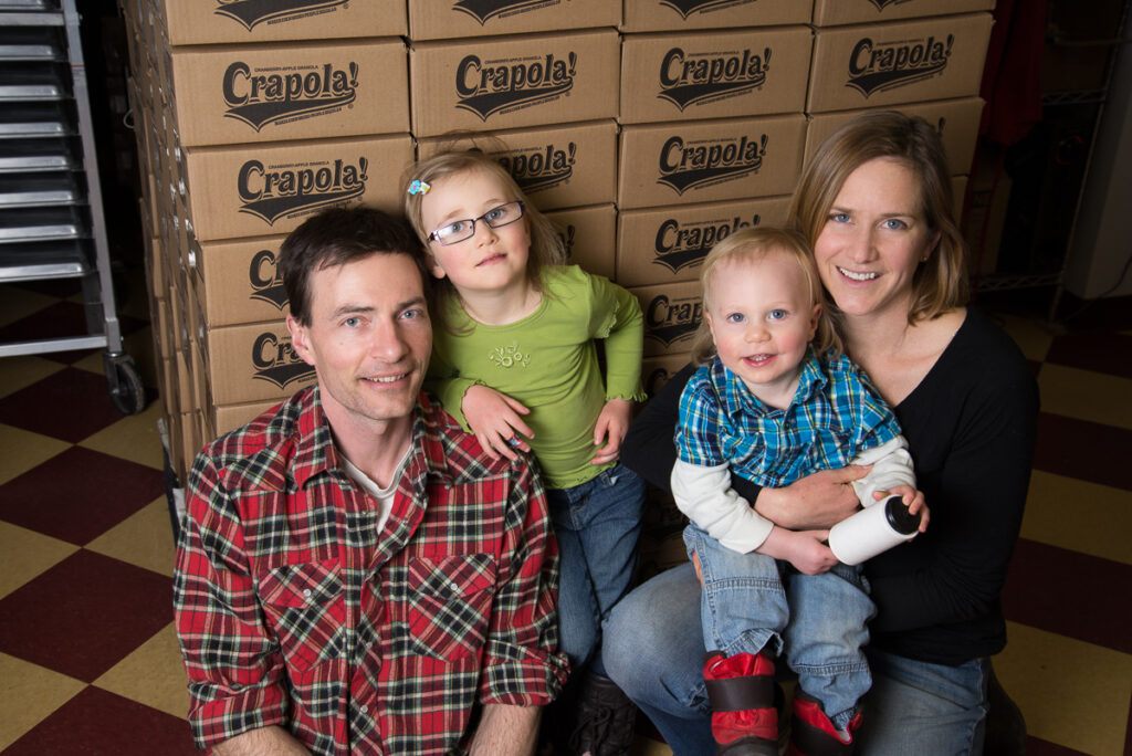 Family of 4 in front of boxes of granola.