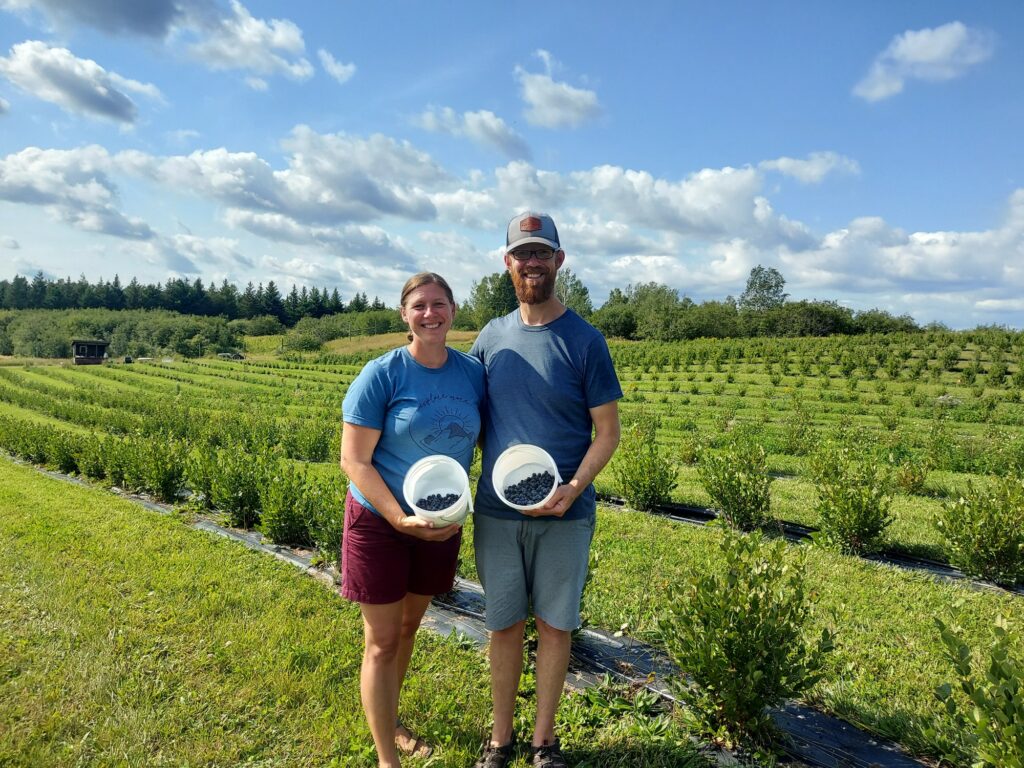 Two people holding tubs of blueberries