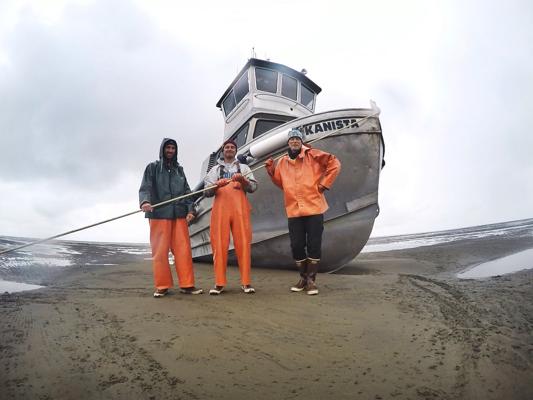 Three people stand next to an Alaskan Fishing Boat
