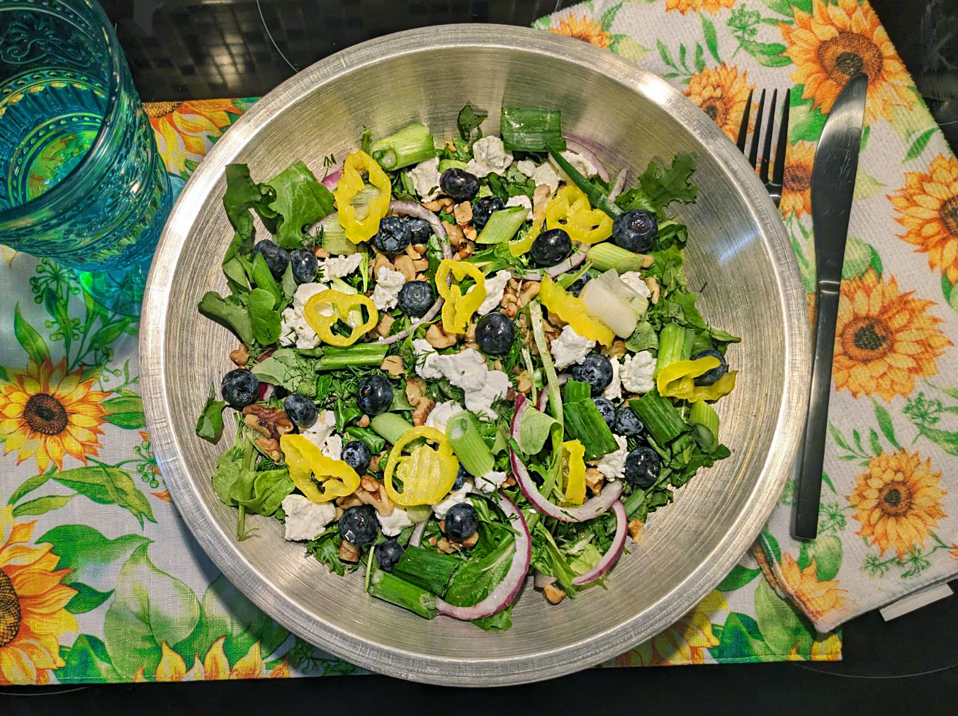 Salad in a bowl with mixed greens, red onions, banana peppers, and blueberries.