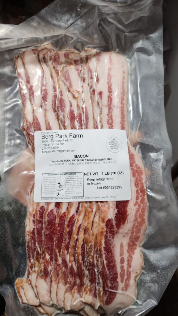 A vacuum-sealed package of bacon from Berg Park Farm. The label on the package displays farm details, ingredients, and weight (1 lb, 16 oz). The bacon slices are visible through the clear packaging.