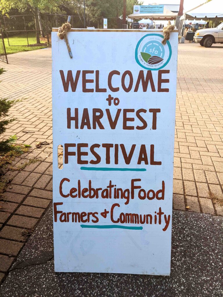 Hand-painted sign that says, Welcome to Harvest Festival, Celebrating Food, Farmers, and Community