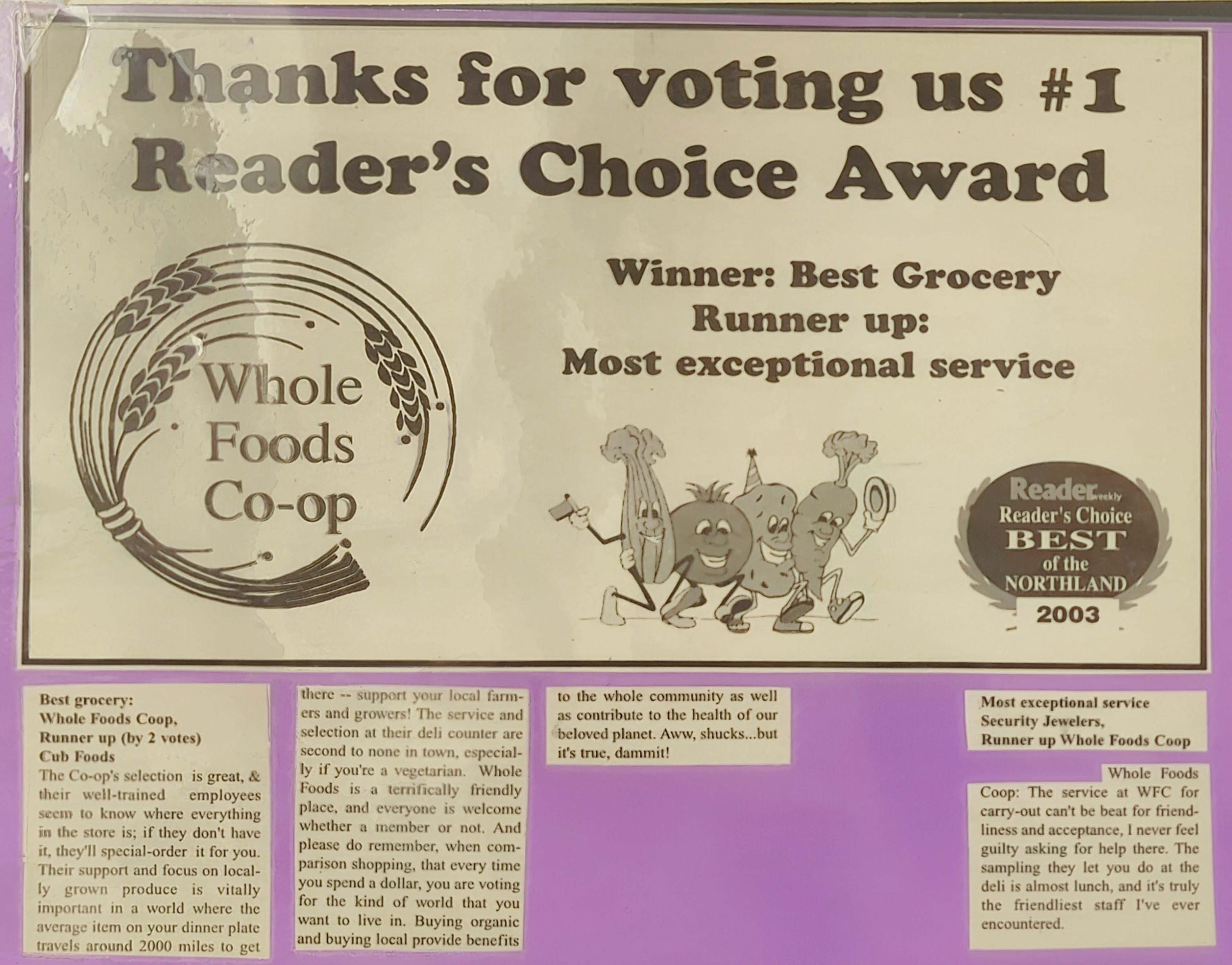 A sign titled "Thanks for voting us #1 Reader's Choice Award," reads "Winner: Best Grocery, Runner up: Most exceptional service," from 2003. Featuring an illustration of anthropomorphic vegetables and the Whole Foods Co-op logo, it highlights the outstanding services at Whole Foods Co-op Duluth MN.