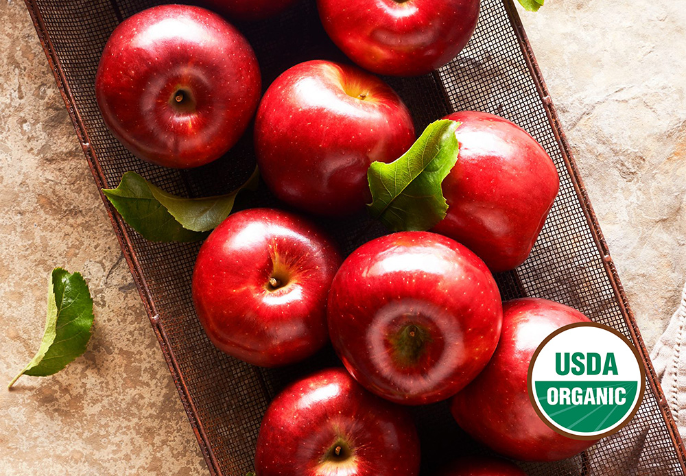 Eight cosmic crisp apples in a wire basket with the USDA organic seal
