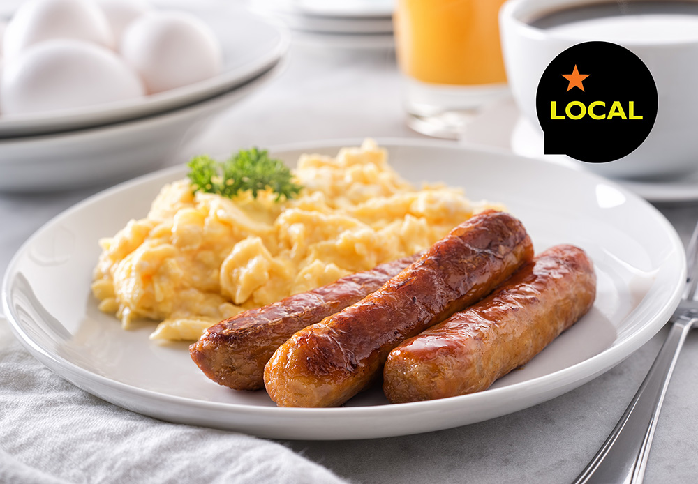 Sausage links on white plate with scrambled eggs and the word 