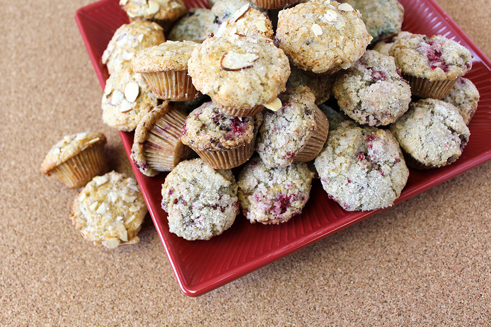 A red square plate overflowing with a pile of cranberry almond muffins.