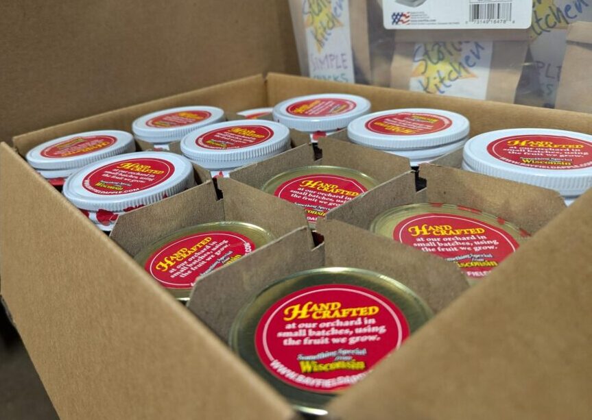 A box full of jars of Wisconsin apple butter with the words "Hand Crafted" on the lid labels.