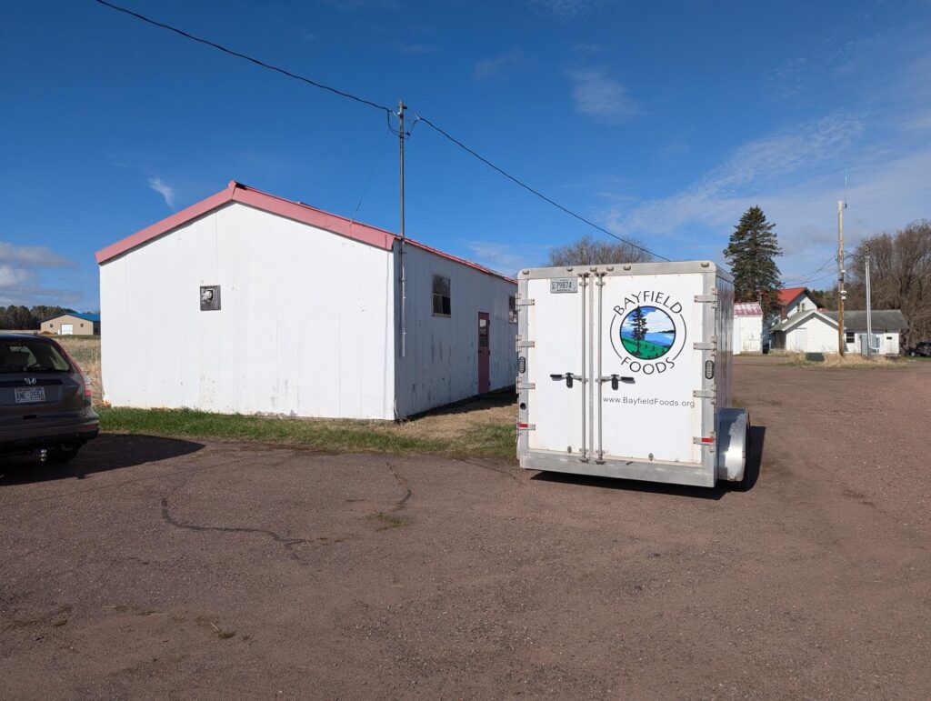 A trailer with the Bayfield Foods logo next to a white building.