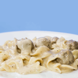 Swedish meatballs and egg noodles on a white plate.
